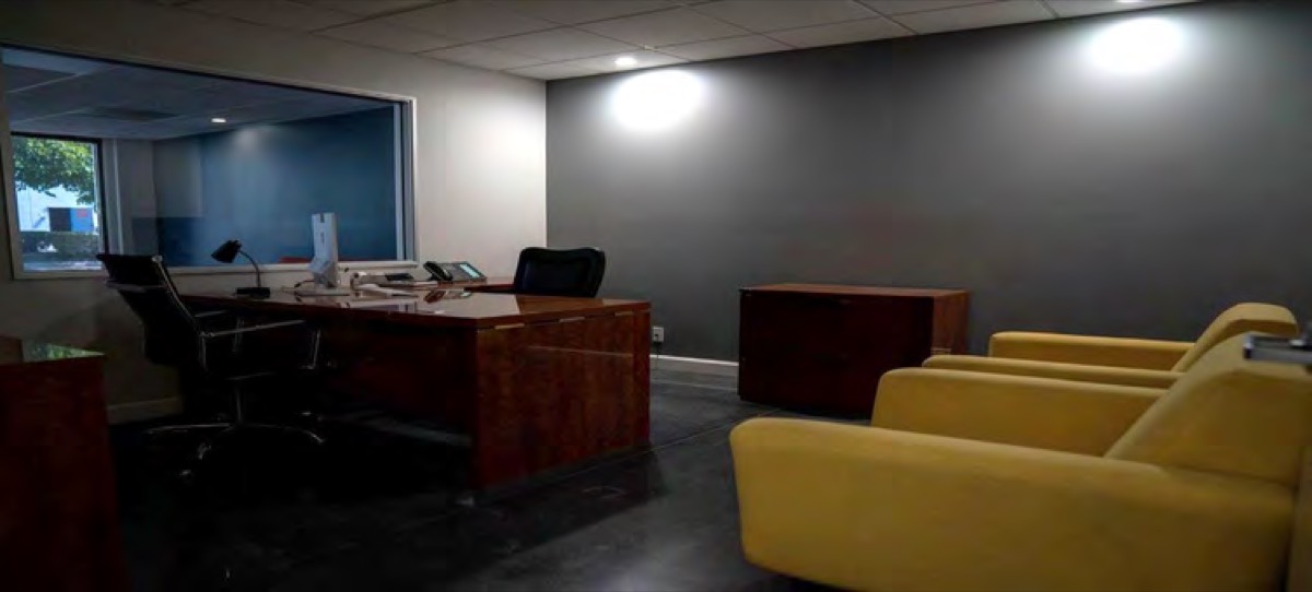 An executive office with a wood desk and yellow armchairs