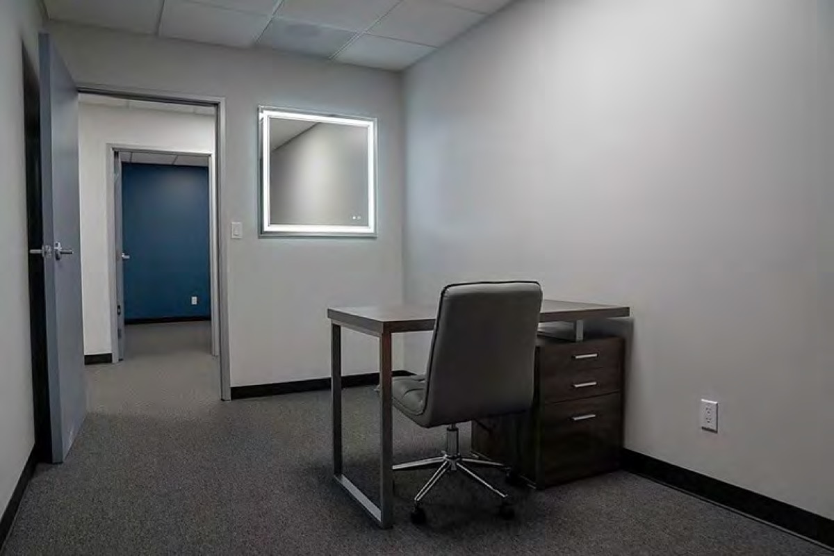 A 9 by 15 foot room with a desk and an orange couch