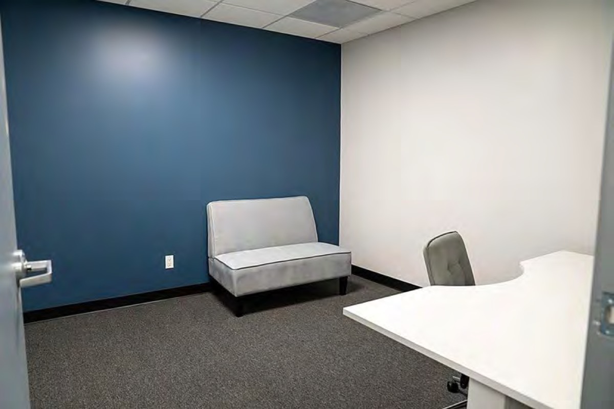 An 11 by 12 foot suite with a sit-stand desk and wall-mounted TV