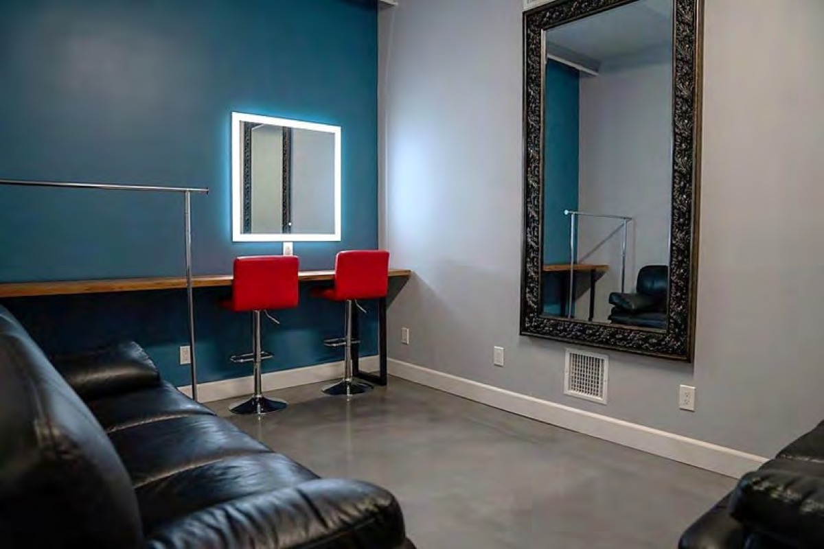 Wardrobe and green room with a lit mirror, rack, and leather couch