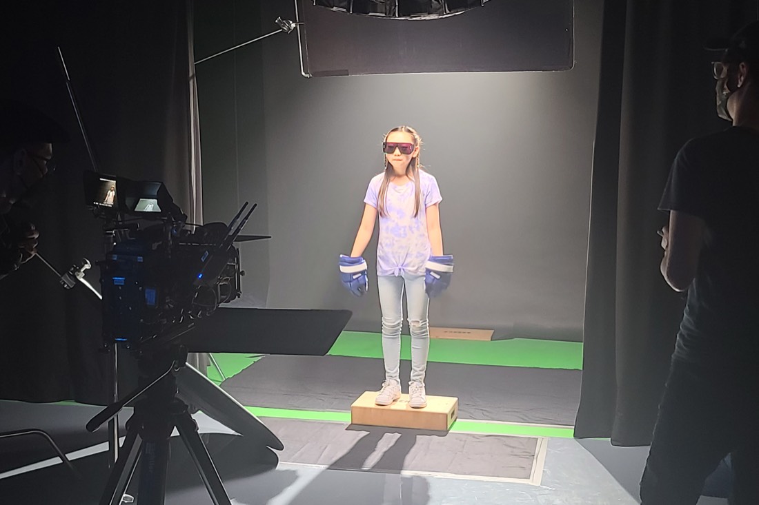 A performer in VR gloves on a mark in front of a camera